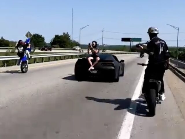Man Sits on Back of C7 Corvette Driving Down Highway